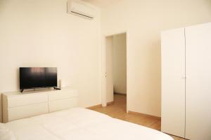 1 dormitorio blanco con TV de pantalla plana en una cómoda en Corsico Comfort Home en Corsico
