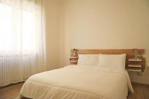 1 dormitorio con 1 cama con sábanas blancas y ventana en Corsico Comfort Home, en Corsico