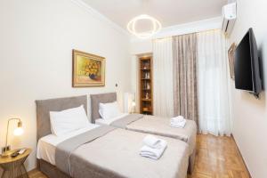 two beds in a small room with a tv at King George 32 Luxury Apartment in Thessaloniki