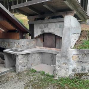 eine Außenküche mit einem Steinofen im Gras in der Unterkunft Wooden Treasure in Jesenice