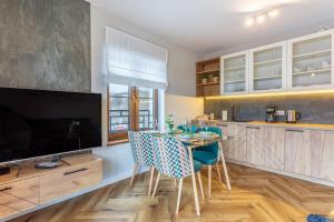 cocina con mesa y sillas y TV en Apart Invest Green Park Resort Apartament A14 Baseny, Sauny, Siłownia, en Szklarska Poręba