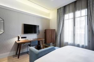 Habitación de hotel con cama, escritorio y TV. en DoubleTree by Hilton Madrid-Prado, en Madrid