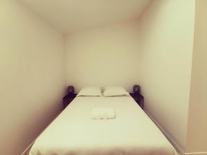 uma cama num pequeno quarto com paredes brancas em Le quai du Rhône em Sainte-Colombe