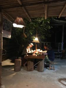 een groep mensen die rond een houten tafel zitten bij Happy Homestay Banlung & Trekking in Banlung