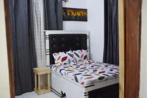 a small bed in a room with black curtains at 2 Bedroom spacious Cozy Home in Kigamboni,10 min Walk to Beach in Dar es Salaam