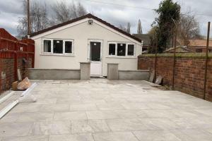a white house with a brick fence and a patio at Guest House Bungalow in Walsall