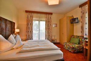 a hotel room with a large bed and a chair at Hotel Villnerhof in Egna