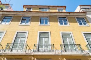 un edificio giallo con finestre e balconi di PedrasNegras30 Lisbon Lofts & Apartments a Lisbona