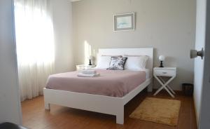 ein weißes Schlafzimmer mit einem Bett und einem Fenster in der Unterkunft House Seven in Horta