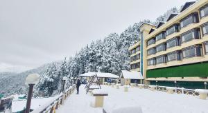 a person standing in the snow in front of a building at Snow Valley Resorts Dalhousie in Dalhousie