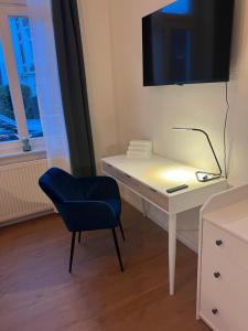 a white desk with a blue chair and a television at Stadtwohnung in Oldenburg