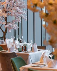 Hotel La Tour في ميلتون كينز: طاولة طعام مع قماش الطاولة البيضاء وشجرة مع الزهور الزهرية