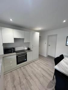 a kitchen with white cabinets and a table in a room at The Harbour Cottage in Peterhead