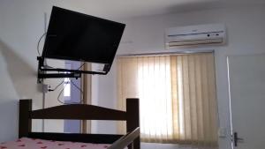 TV de pantalla plana colgada en la pared de una habitación en Pousada Do Léo, en Bertioga