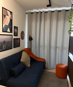 uma sala de estar com um sofá azul em frente a uma janela em Conforto e segurança na avenida Liberdade em São Paulo