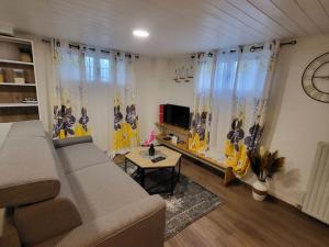 ein Wohnzimmer mit einem Sofa und einem Tisch in der Unterkunft Appartement 2 pièces près du lac de Bouzey in Sanchey