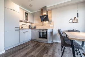 a kitchen with white cabinets and a wooden table at Gersten-Koje in Büsum