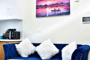 a blue couch with white pillows sitting under a painting at Kandiz Exquisite in Nairobi