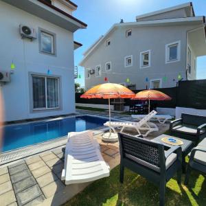 un patio con 2 sombrillas y una piscina en Villa Can Fethiye, en Fethiye