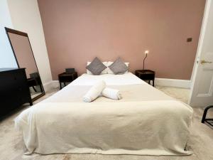 een slaapkamer met een groot bed met witte lakens en kussens bij Cosy Glasgow Retreat with Modern Amenities in Glasgow