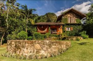 a house with a stone wall in front of it at Refúgio Farm House in Paraty