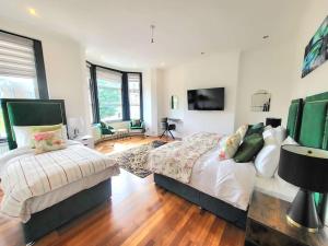 a bedroom with two beds and a flat screen tv at Sensational Room Stays- Callcott Road in London