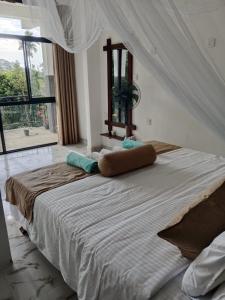 ein großes Bett in einem Zimmer mit einem großen Fenster in der Unterkunft Freedom Safari Cottage in Udawalawe