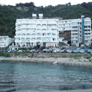 um grande edifício branco ao lado de uma massa de água em Mona em Ulcinj