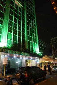 ein Auto, das vor einem Gebäude mit grüner Beleuchtung parkt in der Unterkunft Terrazzo Hotel in Campos dos Goytacazes