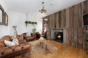 a living room with leather couches and a fireplace at Jacobite Lodge by The House of Danu in Kingussie