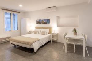 - une chambre blanche avec un lit et une table dans l'établissement Faro Downtown Ria Formosa Studios, à Faro