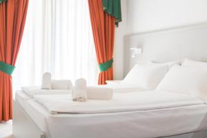 two white beds in a room with orange curtains at Hotel Garda Bellevue in Limone sul Garda