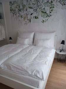 a white bed with a floral mural on the wall at APARTMÁN in Turčianske Teplice