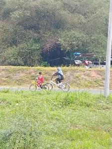a man and a child riding bikes on a road at Homestay Hulu Langat with POOL and RIVER Free Fishing Village Panorama WiFi and Netflix in Hulu Langat