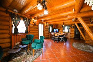 a living room of a log cabin with green chairs and a table at Casa de Lemn in Râşnov