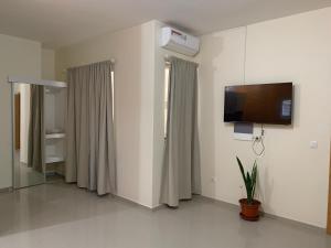 Habitación hospitalaria con TV de pantalla plana en la pared en J Martins Apart Hotel en Tarrafal