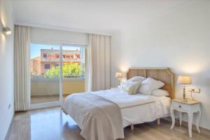 a white bedroom with a bed and a large window at modern apartment by the sea.(Marbella) in Marbella