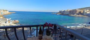 einen Balkon mit Weinflaschen und Meerblick in der Unterkunft Marsalforn Sea Front Studio in Żebbuġ