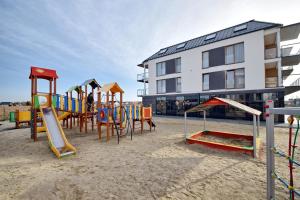 a playground in the sand next to a building at Przystań Apartamenty Sarbinowo in Sarbinowo