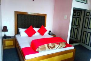 um quarto com uma cama grande e almofadas vermelhas em Hotel North Point Darjeeling - Excellent Service Recommended & Couple Friendly em Darjeeling