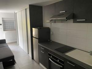 a kitchen with a black counter and a refrigerator at Studio moderne entièrement rénové. in Freistroff