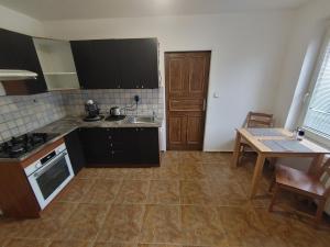 cocina con armarios negros, mesa, mesa y mesa en Privat Apartment Zdenko, en Ostrava
