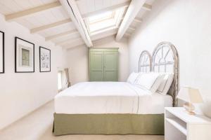 - une chambre blanche avec un lit blanc et une porte verte dans l'établissement VerdeOlivo 1876, à Mezzane di Sotto