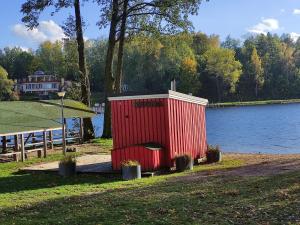 una casa roja al lado de un lago en Stranda, en Giżycko