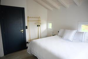 sypialnia z białym łóżkiem i czarnymi drzwiami w obiekcie Hotel Neguetxea w mieście Guernica y Luno