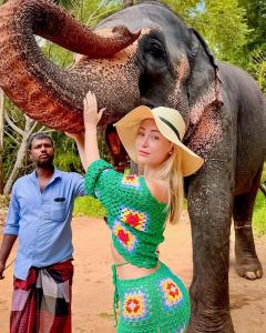 a woman in a green dress standing next to an elephant at Freedom Safari Cottage in Udawalawe