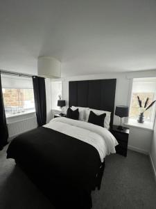une chambre avec un grand lit et deux fenêtres dans l'établissement The Harbour Cottage, à Peterhead