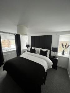 a bedroom with a large bed and two windows at The Harbour Cottage in Peterhead