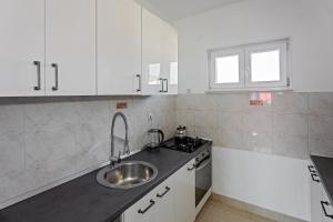 a kitchen with white cabinets and a sink and a window at Apartment Zlatko in Rogoznica +72 photos