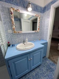 een blauwe badkamer met een wastafel en een spiegel bij Casa vacanze Valledoria Q8732 in Valledoria